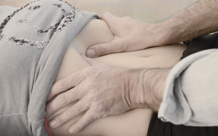 Was ist Osteopathie? Die Hände des Osteopathen untersuchen eine Patientin